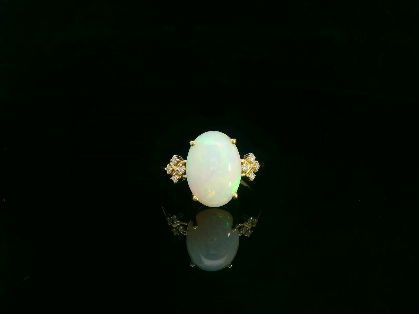 Oval cabochon opal ring in 18K yellow gold with diamond accents by Emirates Diamonds
