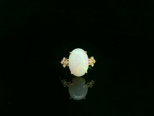 Oval cabochon opal ring in 18K yellow gold with diamond accents by Emirates Diamonds