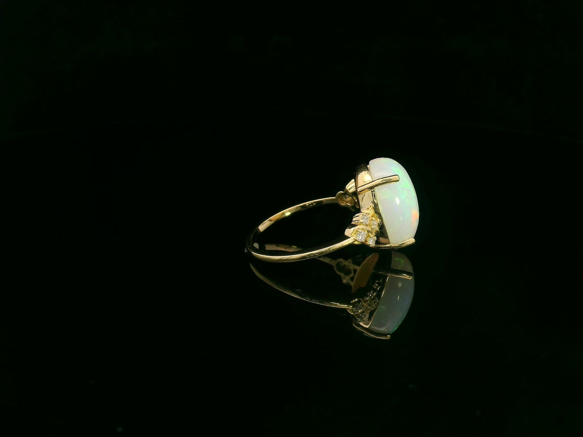 Oval cabochon opal ring in 18K yellow gold with diamond accents by Emirates Diamonds