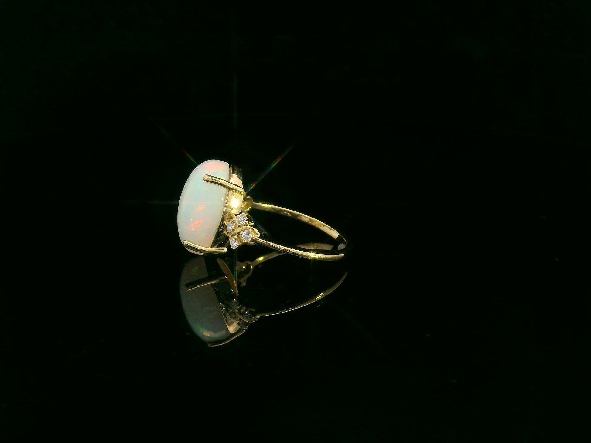 Oval cabochon opal ring in 18K yellow gold with diamond accents by Emirates Diamonds