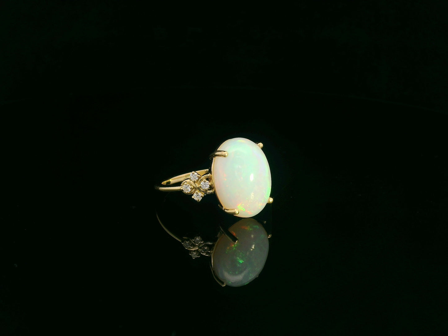 Oval cabochon opal ring in 18K yellow gold with diamond accents by Emirates Diamonds