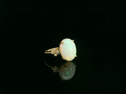 Oval cabochon opal ring in 18K yellow gold with diamond accents by Emirates Diamonds