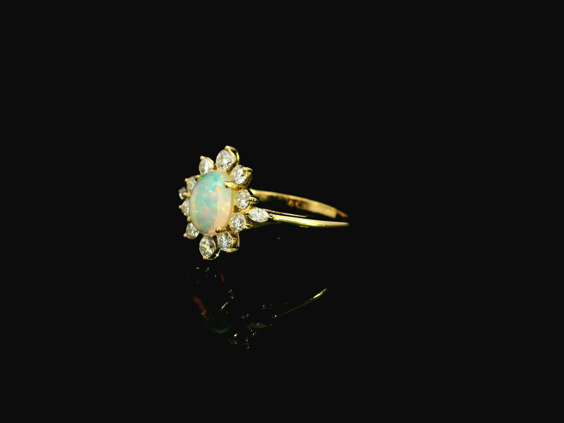Oval opal diamond halo ring in 18K yellow gold with sunburst cluster design Emirates Diamonds