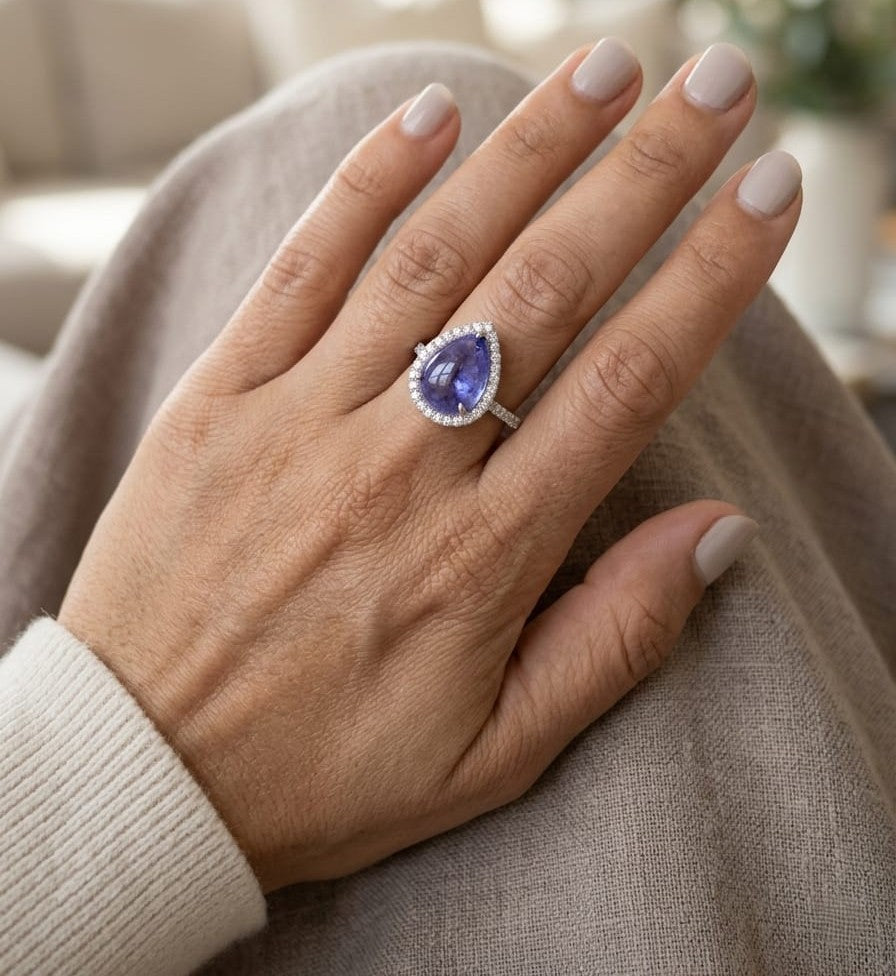 Cabochon tanzanite diamond halo ring in 18K white gold with pear-shaped blue gemstone