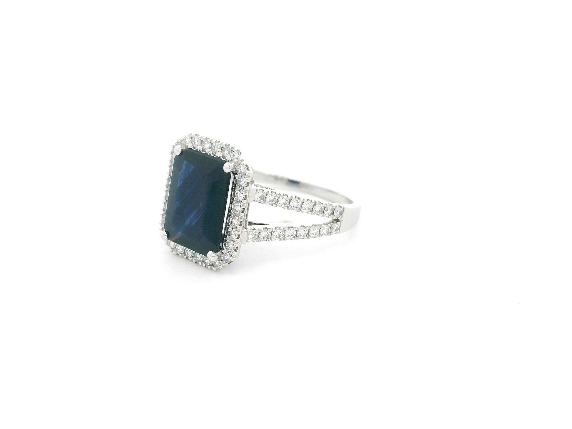 Emerald cut blue sapphire halo ring in 18K white gold with diamond split band Emirates Diamonds