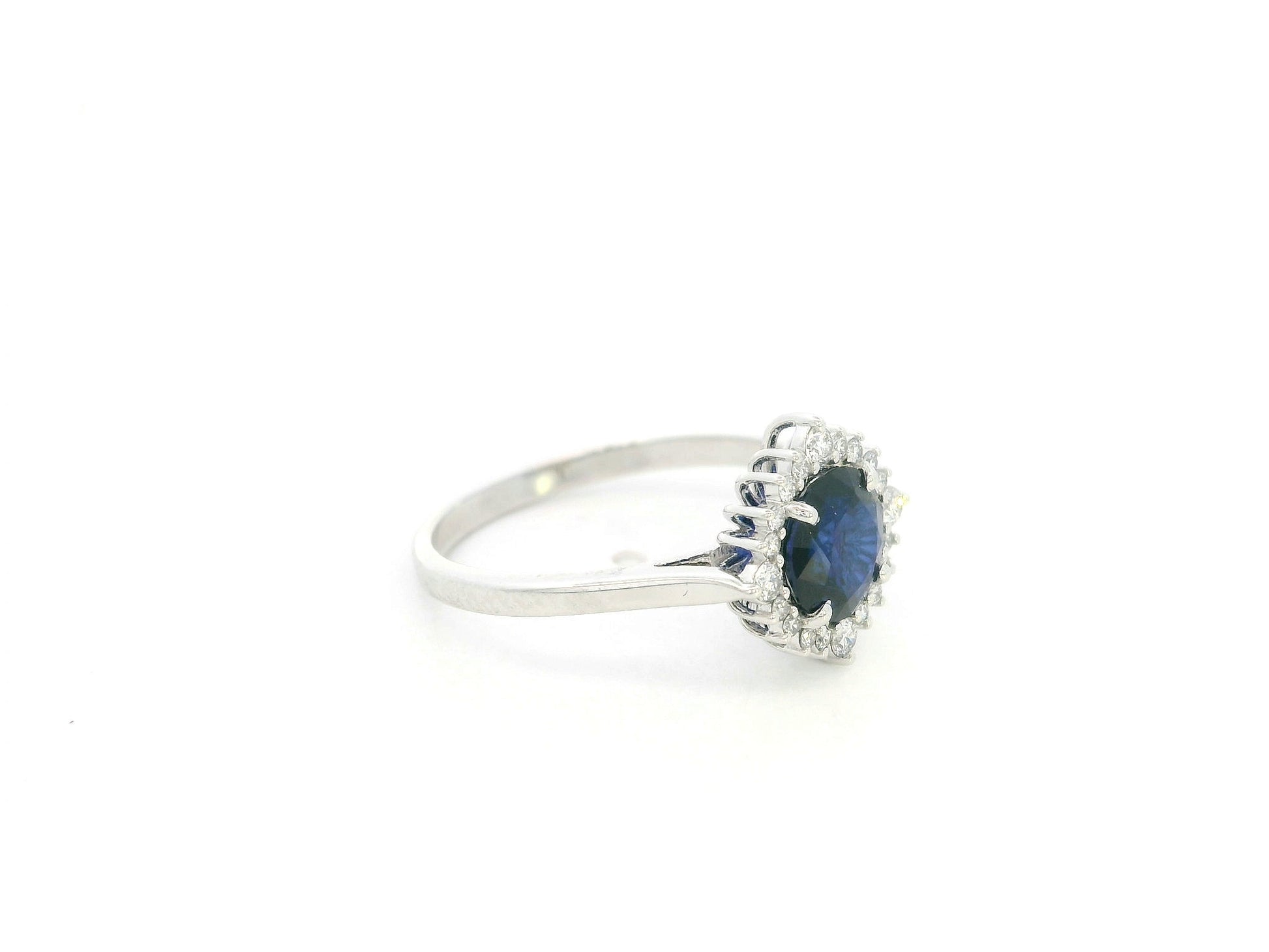 Blue sapphire and diamond halo ring in 18K white gold featuring a 1.24 carat natural blue sapphire and 0.18 carat diamonds