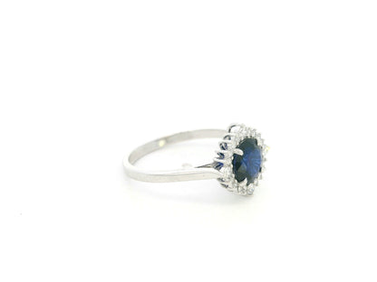 Blue sapphire and diamond halo ring in 18K white gold featuring a 1.24 carat natural blue sapphire and 0.18 carat diamonds