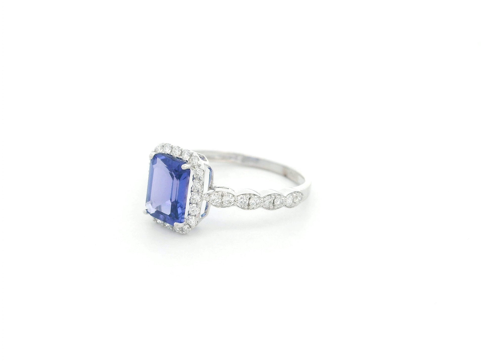 Emerald cut tanzanite halo ring in 18K white gold with marquise diamond band