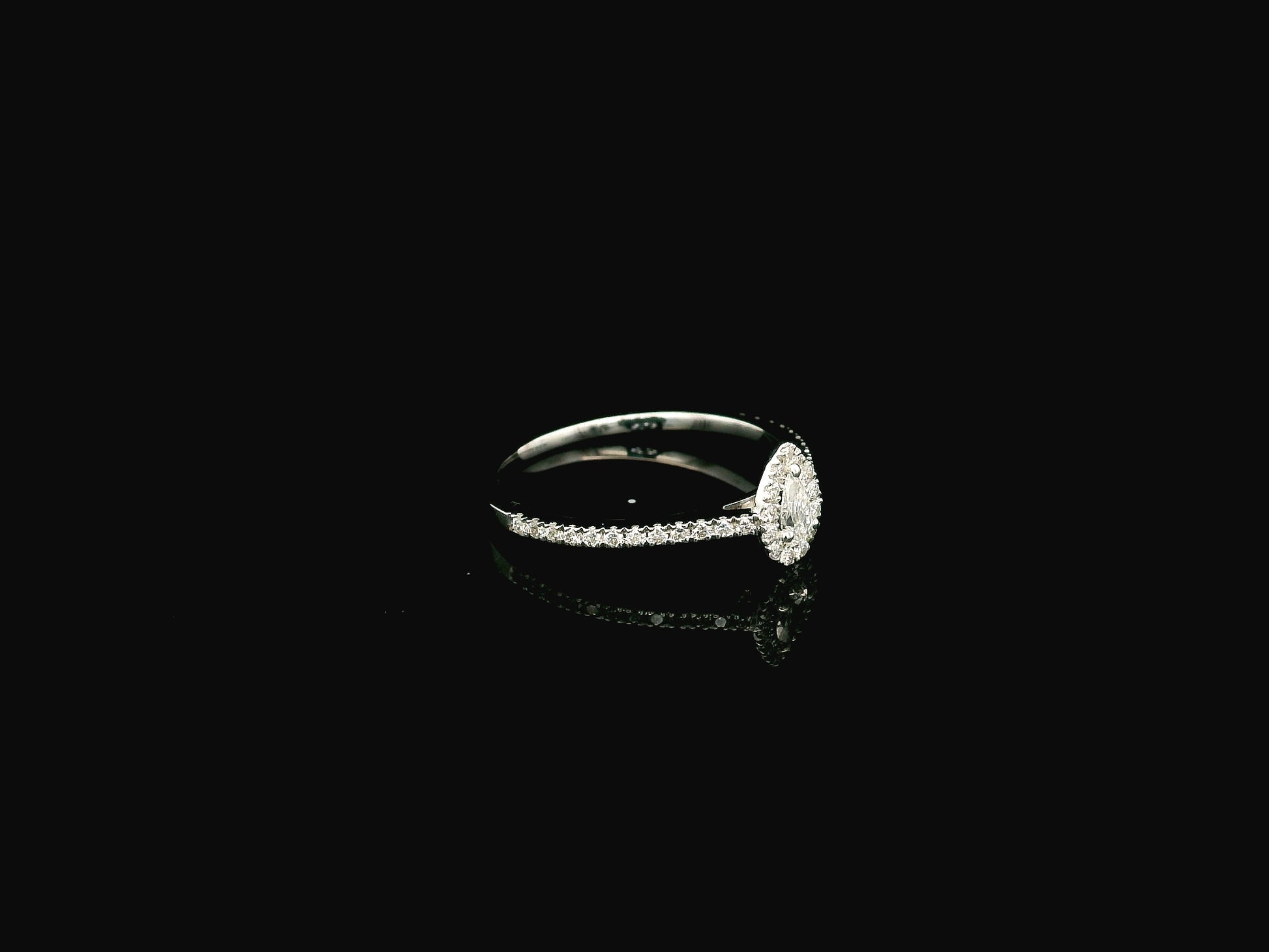Natural pear shape diamond halo ring in solid 18K white gold featuring a pear-shaped centre diamond with a round brilliant diamond halo and pavé diamond band.
