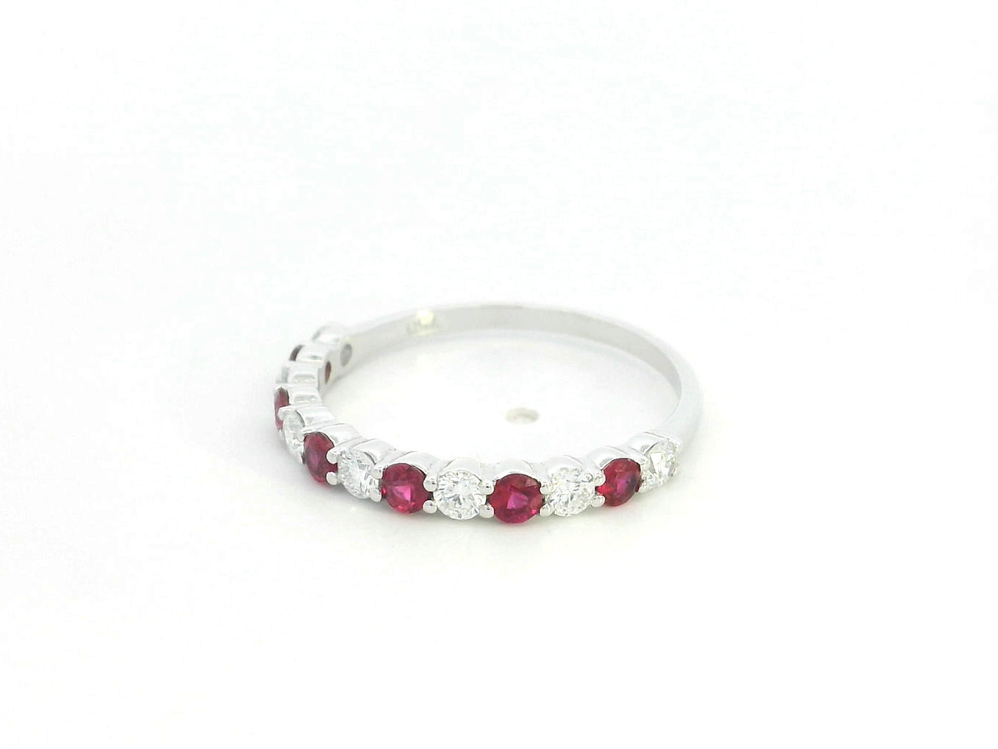 Ruby and diamond half eternity ring in 18K white gold with alternating round rubies and diamonds.