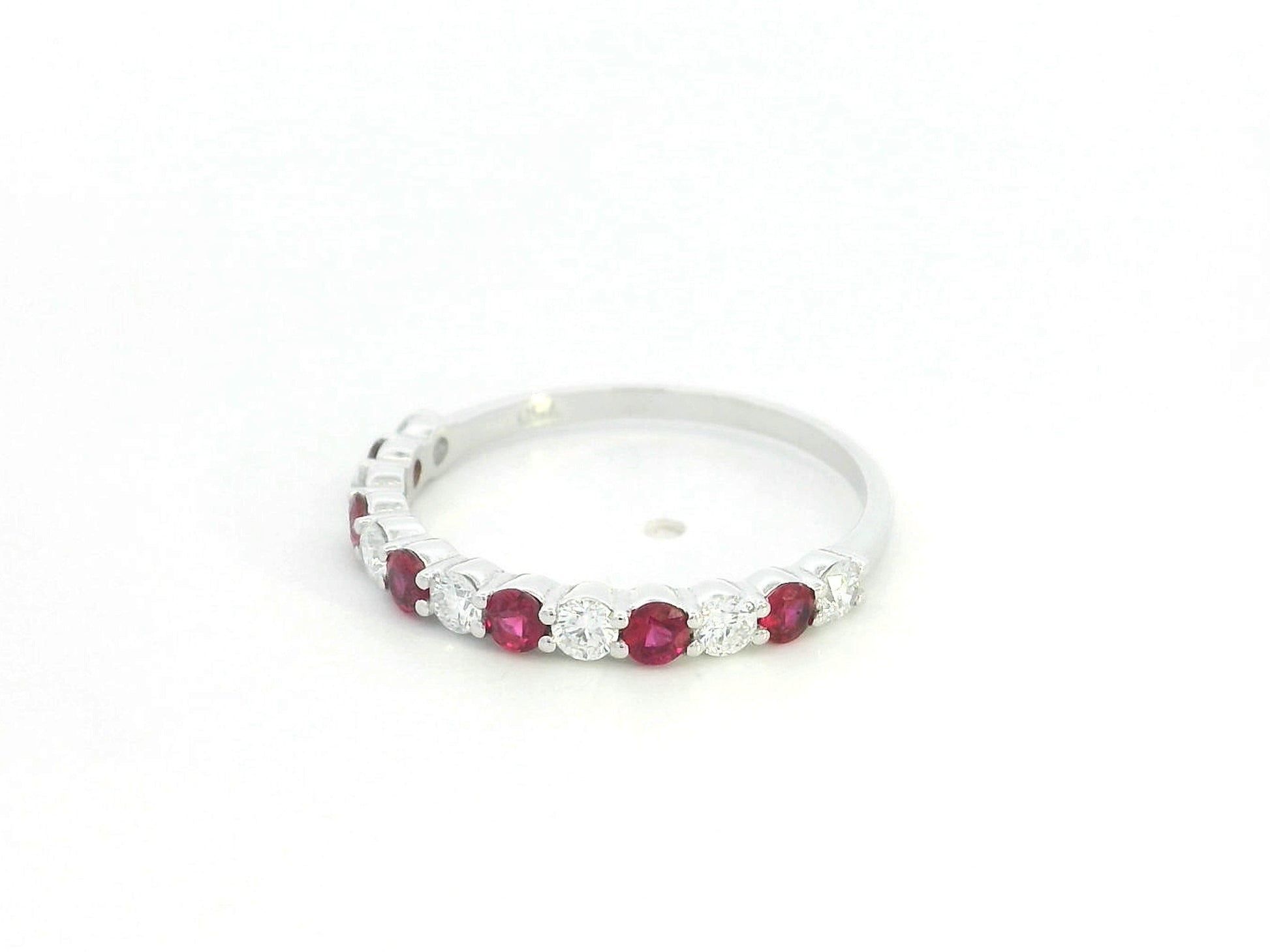 Ruby and diamond half eternity ring in 18K white gold with alternating round rubies and diamonds.
