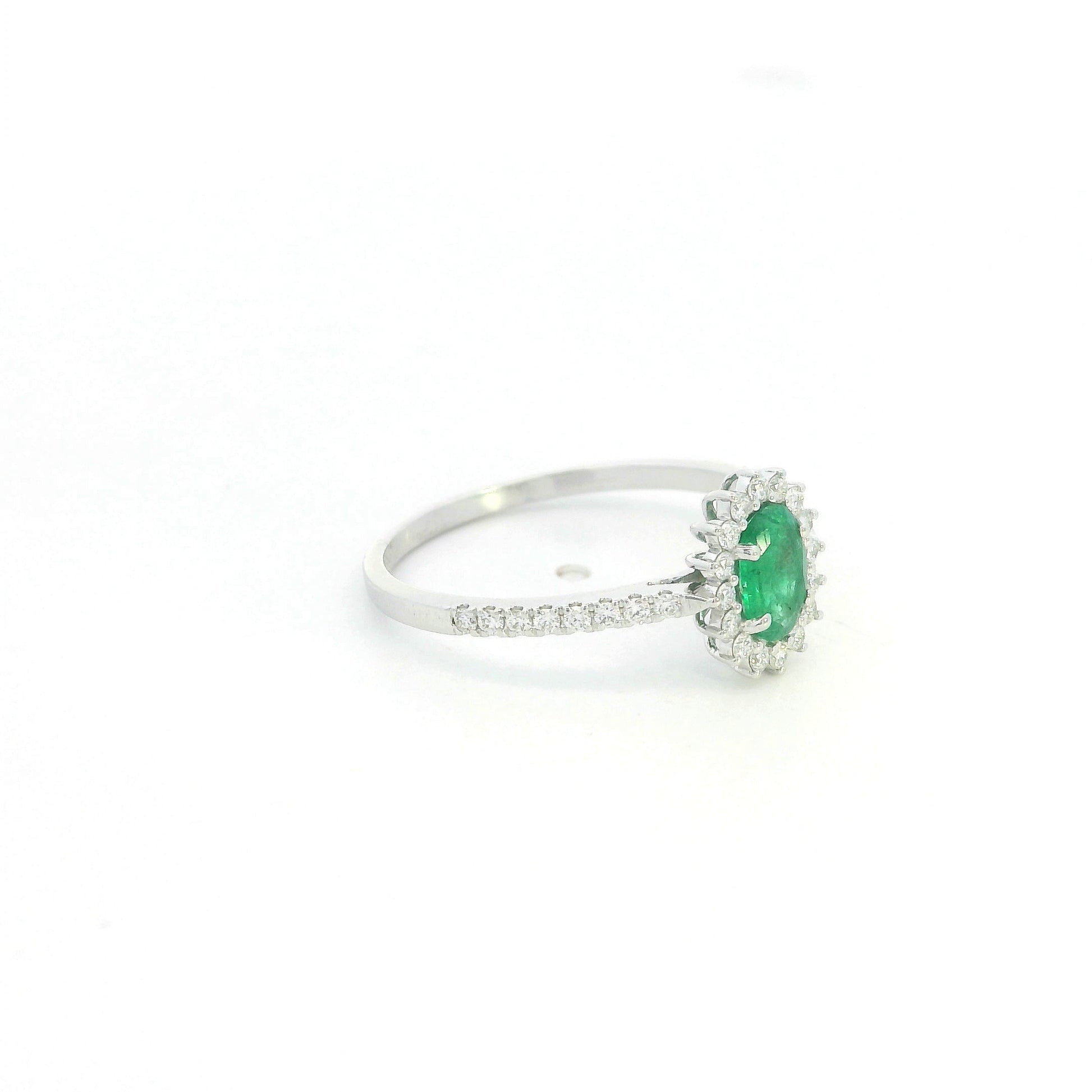 Natural oval emerald ring in 18K white gold featuring a 0.35 carat emerald surrounded by a diamond halo with 0.23 carat total diamond weight.