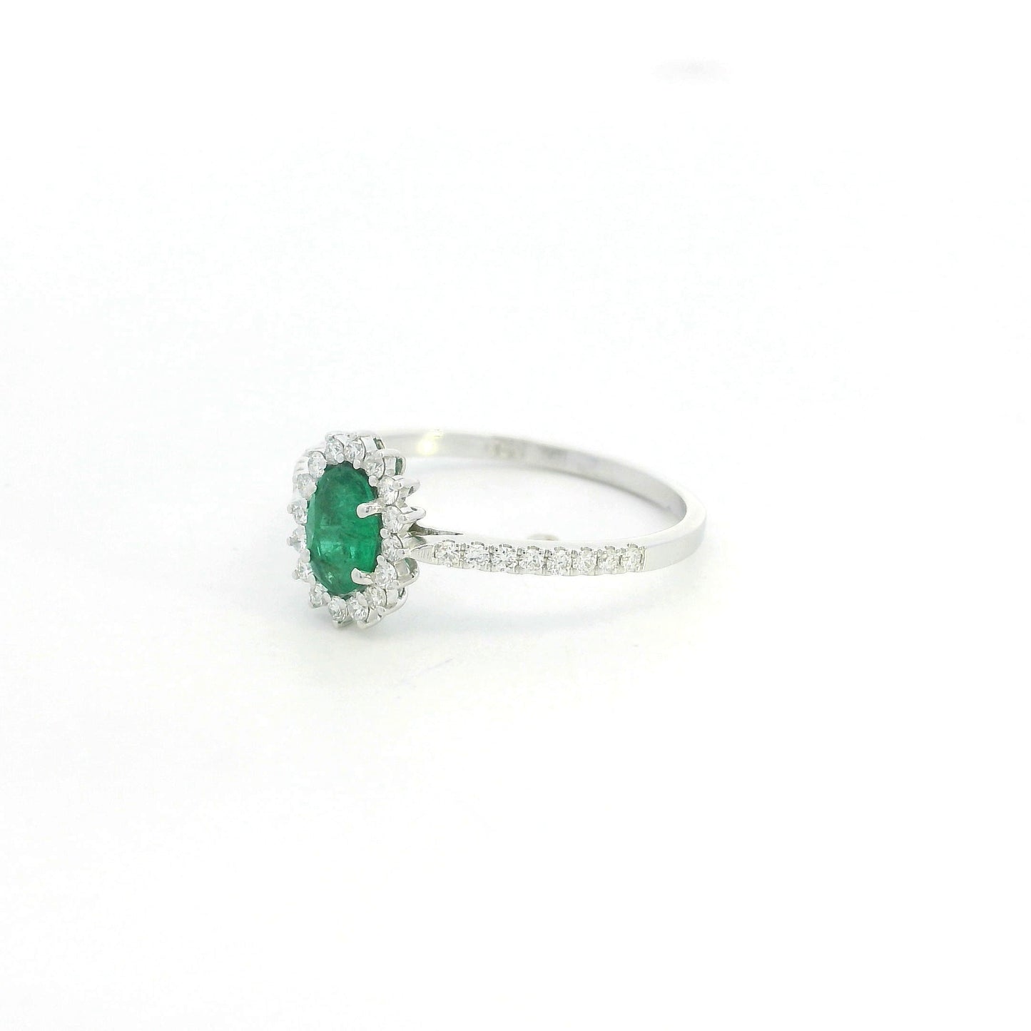 Natural oval emerald ring in 18K white gold featuring a 0.35 carat emerald surrounded by a diamond halo with 0.23 carat total diamond weight.
