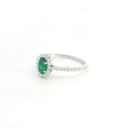 Natural oval emerald ring in 18K white gold featuring a 0.35 carat emerald surrounded by a diamond halo with 0.23 carat total diamond weight.
