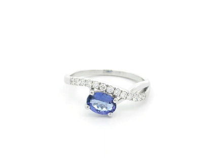 18K white gold tanzanite ring featuring a 0.70 carat oval-cut tanzanite and 0.23 carats of natural diamonds in a crossover design.