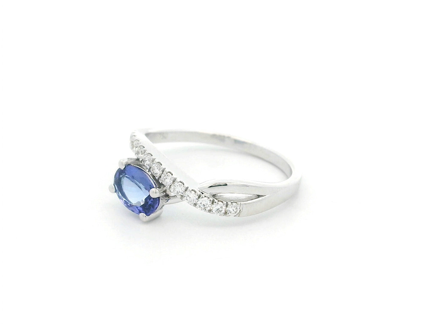 18K white gold tanzanite ring featuring a 0.70 carat oval-cut tanzanite and 0.23 carats of natural diamonds in a crossover design.