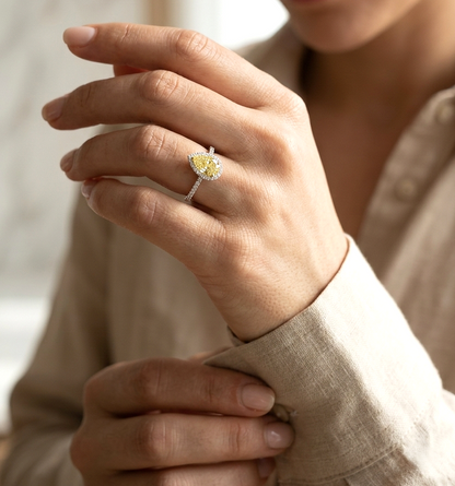 Fancy yellow pear-shaped diamond halo ring in 18K white gold with pavé diamond band and GIA certified center stone.