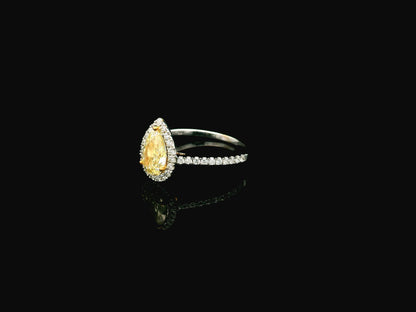 Fancy yellow pear-shaped diamond halo ring in 18K white gold with pavé diamond band and GIA certified center stone.