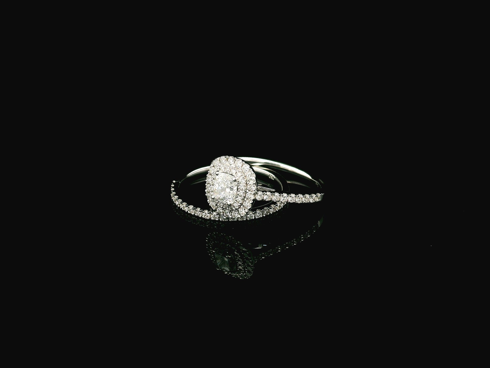 GIA certified cushion cut diamond bridal ring set in 18K white gold with halo engagement ring and matching diamond wedding band.