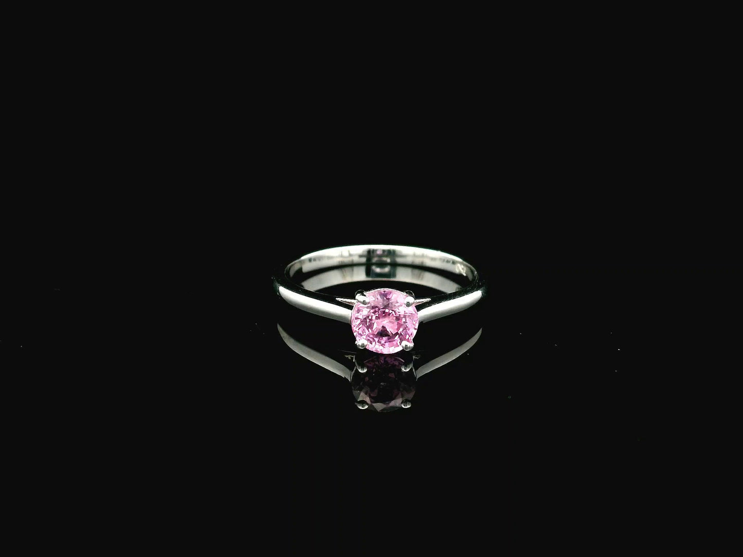 18K white gold pink sapphire solitaire ring featuring a 0.91 carat round pink sapphire in a classic four-prong setting