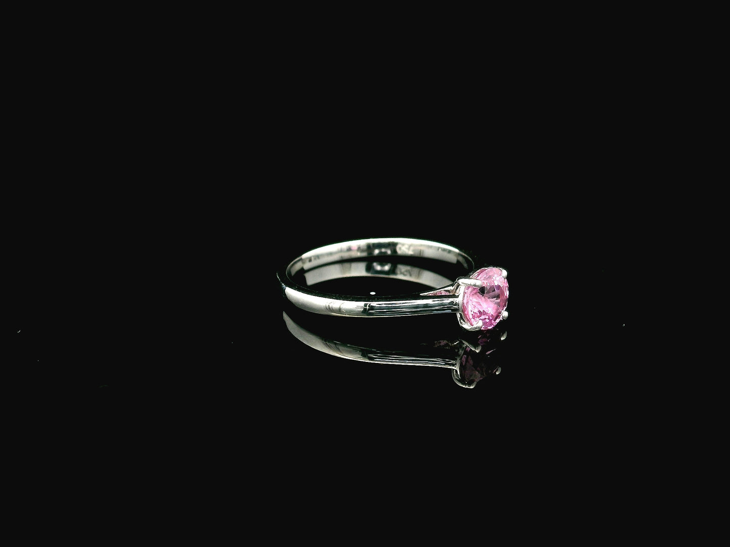 18K white gold pink sapphire solitaire ring featuring a 0.91 carat round pink sapphire in a classic four-prong setting