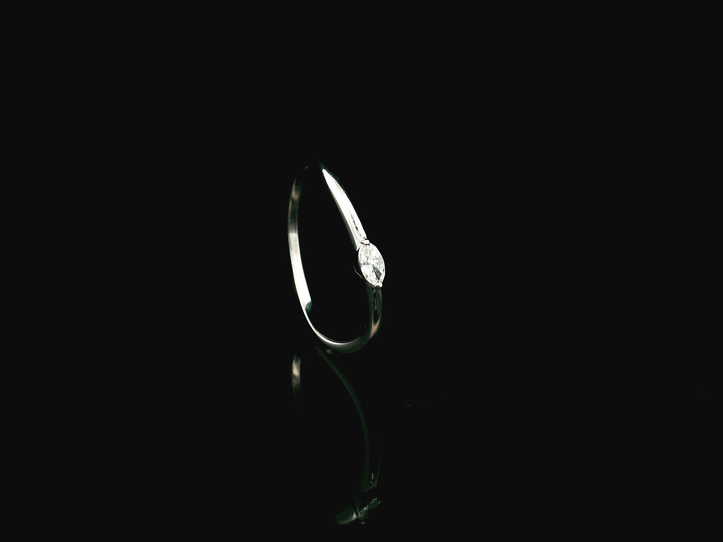 18K white gold solitaire ring featuring a 0.09 carat marquise cut natural diamond in a classic prong setting.