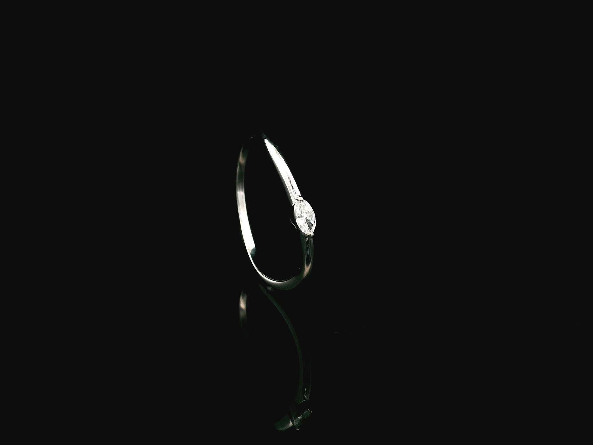 18K white gold solitaire ring featuring a 0.09 carat marquise cut natural diamond in a classic prong setting.