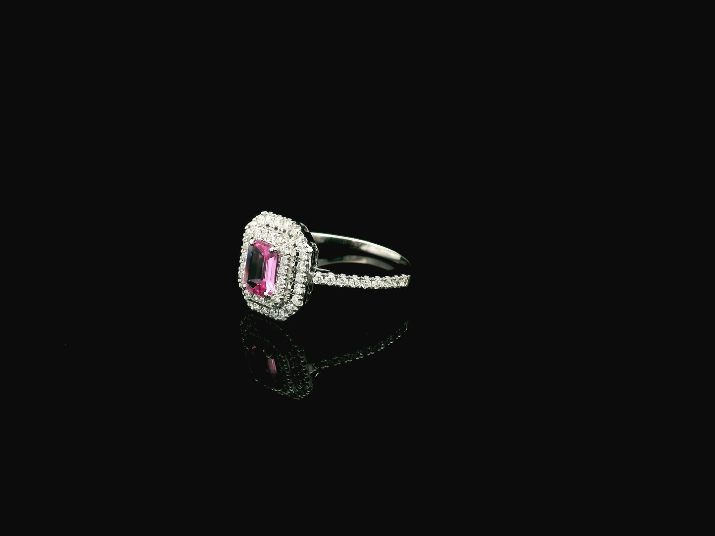 18K white gold pink sapphire halo ring featuring a 0.55 carat emerald-cut pink sapphire surrounded by a double halo of natural diamonds totaling 0.40 carat.