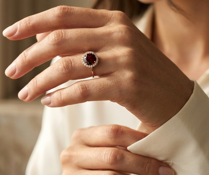 Garnet halo ring in 18K yellow gold featuring a 2.24 carat round garnet surrounded by natural diamonds
