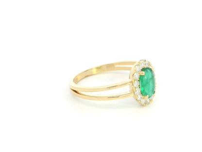 18K yellow gold emerald halo ring featuring a 0.56 carat oval natural emerald surrounded by a 0.28 carat natural diamond halo with an elegant split-band design.