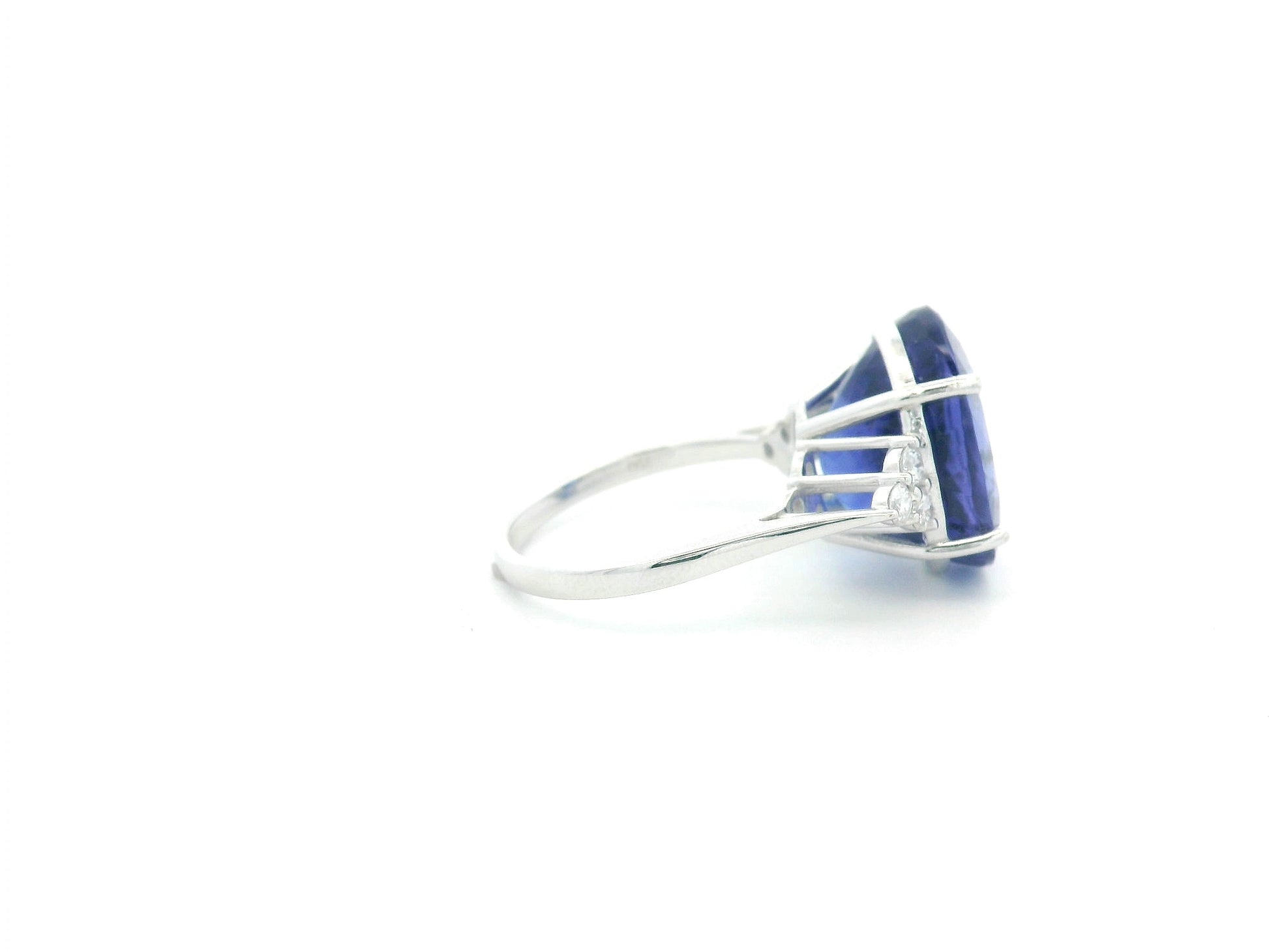 Natural 14.12 carat oval tanzanite and diamond ring in 18K white gold with natural diamond shoulders.