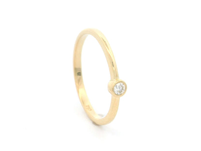 18K yellow gold bezel set diamond ring featuring a 0.07 carat natural round brilliant diamond in a minimalist solitaire design.