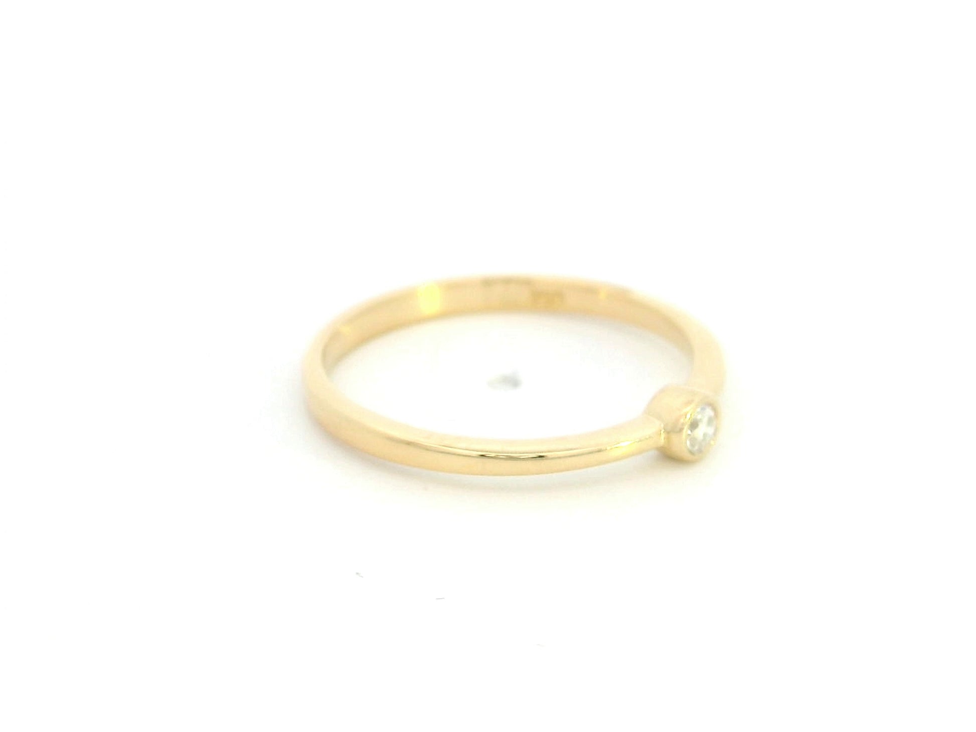 18K yellow gold bezel set diamond ring featuring a 0.07 carat natural round brilliant diamond in a minimalist solitaire design.