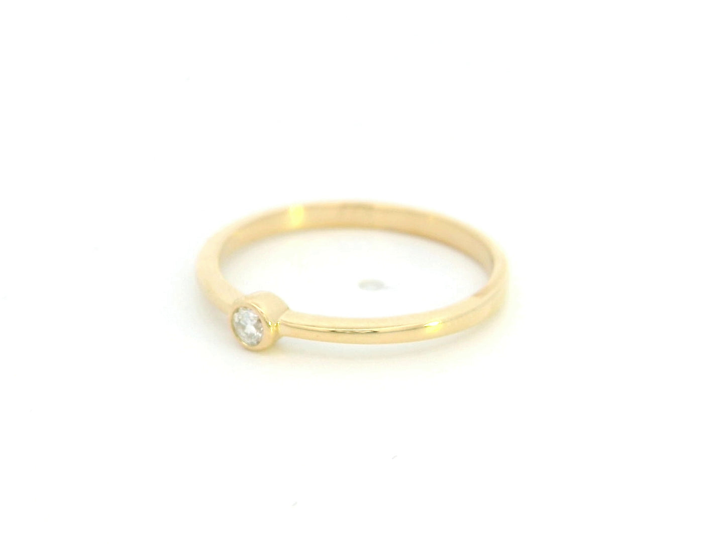 18K yellow gold bezel set diamond ring featuring a 0.07 carat natural round brilliant diamond in a minimalist solitaire design.