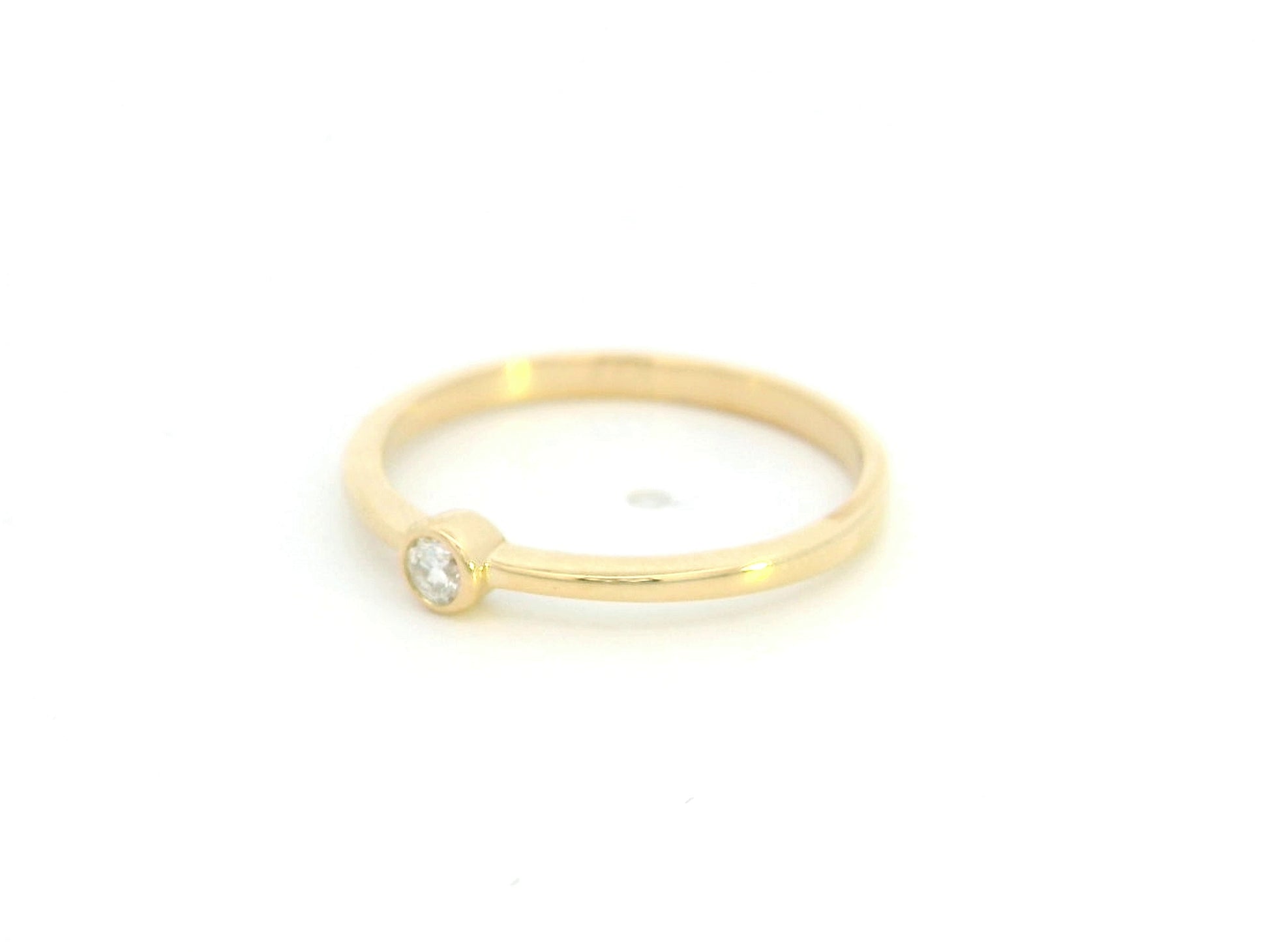 18K yellow gold bezel set diamond ring featuring a 0.07 carat natural round brilliant diamond in a minimalist solitaire design.