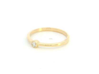 18K yellow gold bezel set diamond ring featuring a 0.07 carat natural round brilliant diamond in a minimalist solitaire design.