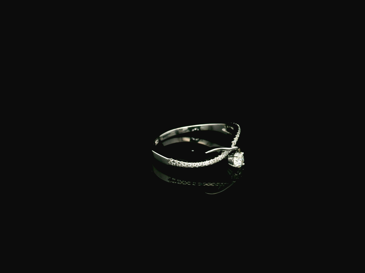 Elegant 18K white gold twist diamond ring featuring a brilliant round centre diamond with flowing pavé diamond crossover band by Emirates Diamonds.