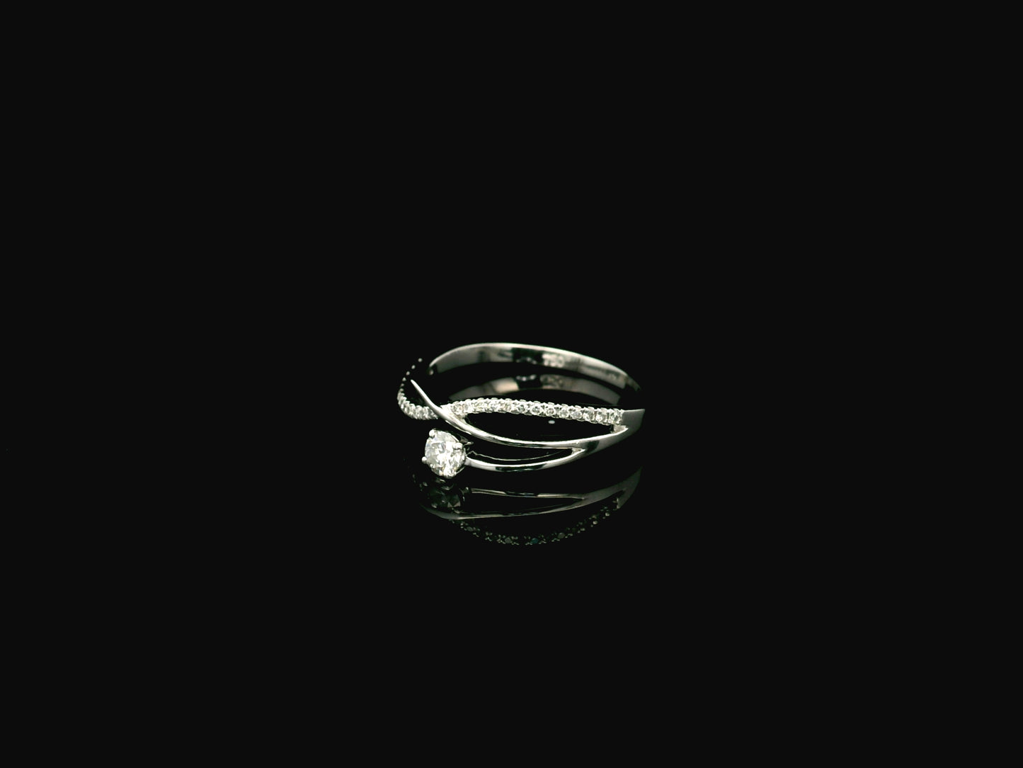 Elegant 18K white gold twist diamond ring featuring a brilliant round centre diamond with flowing pavé diamond crossover band by Emirates Diamonds.