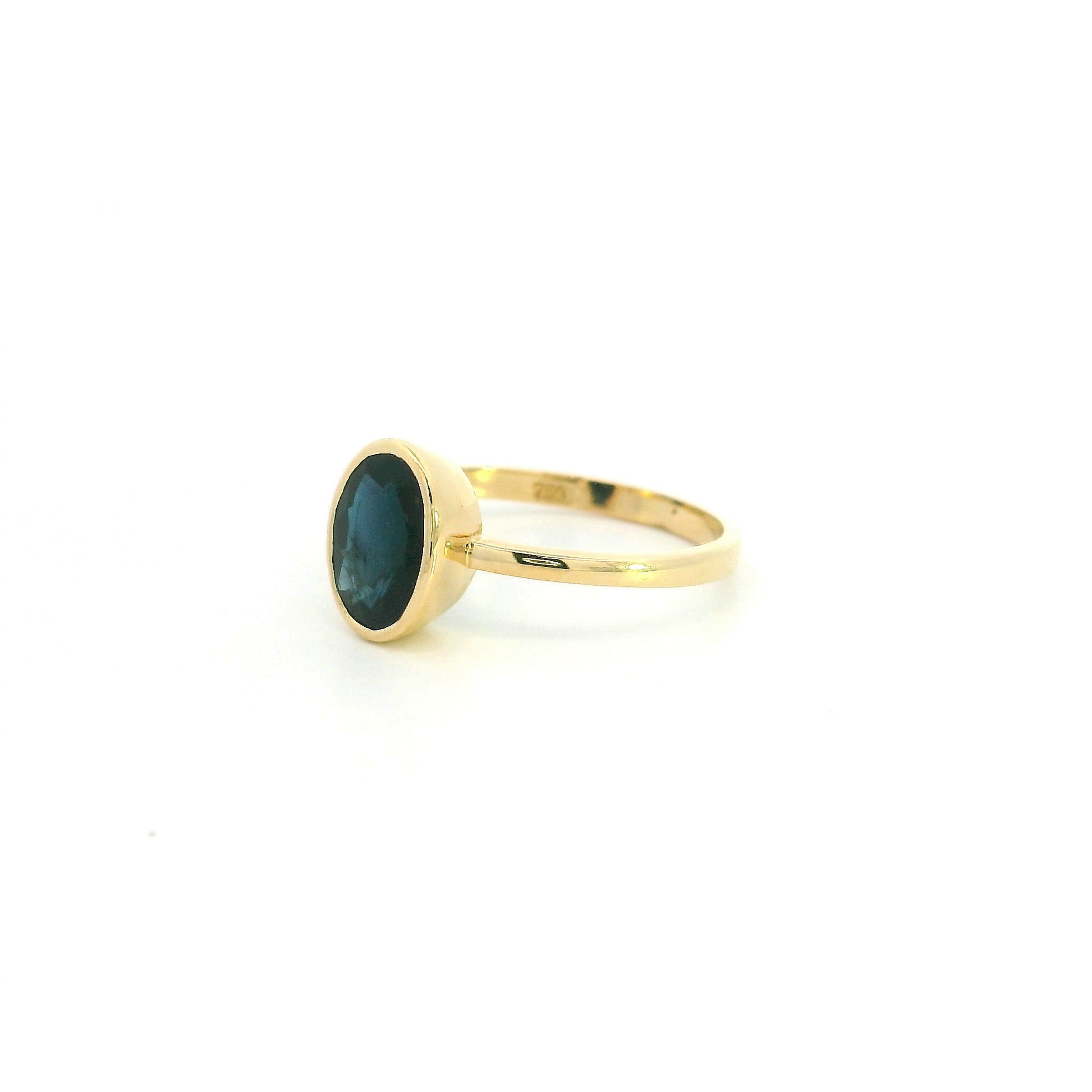 18K yellow gold oval blue sapphire bezel ring featuring a 2.19 Carat natural sapphire in a modern solitaire design.