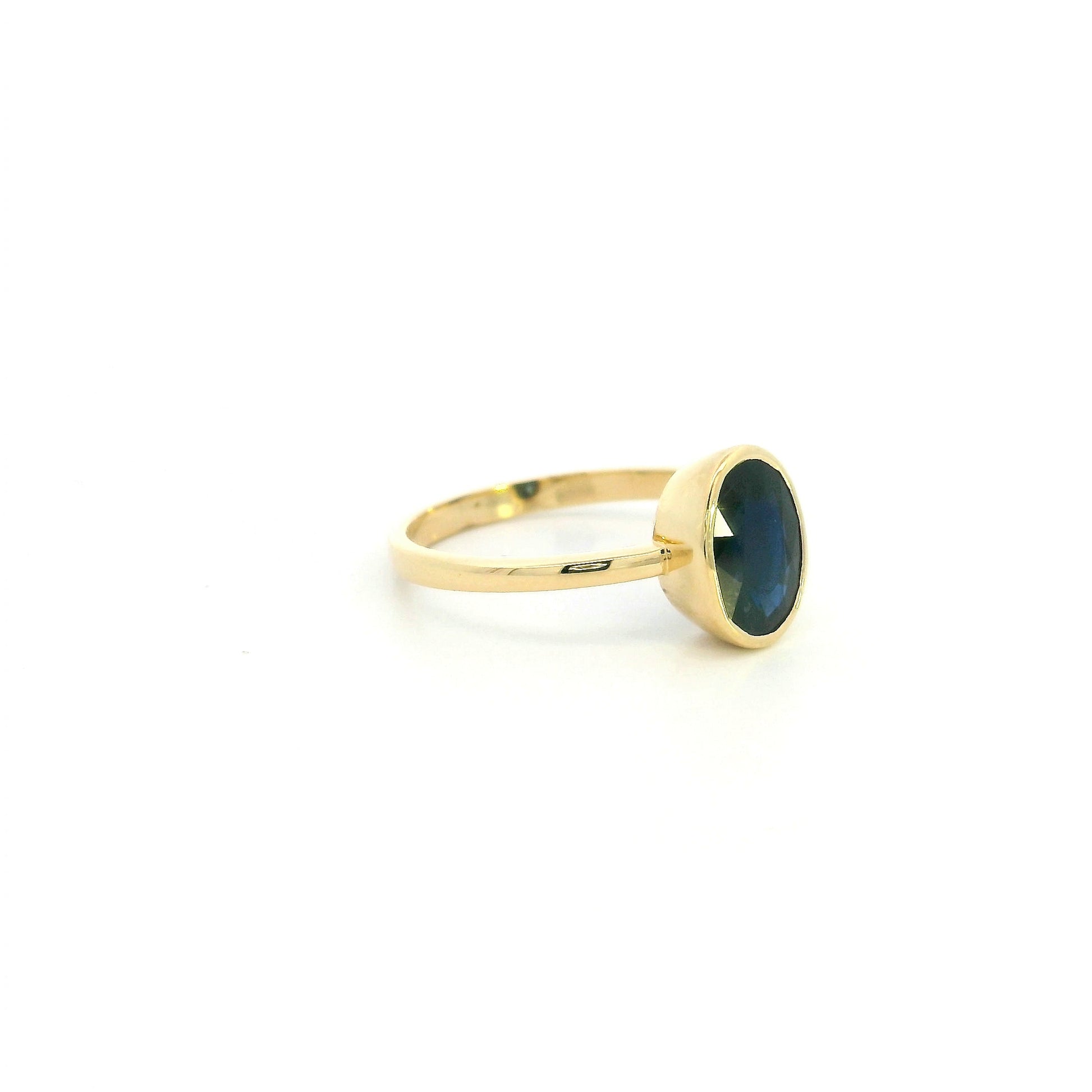 18K yellow gold oval blue sapphire bezel ring featuring a 2.19 Carat natural sapphire in a modern solitaire design.