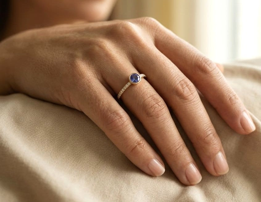 18K yellow gold bezel blue sapphire diamond ring featuring a 0.62 Carat natural round sapphire with diamond-set shoulders.