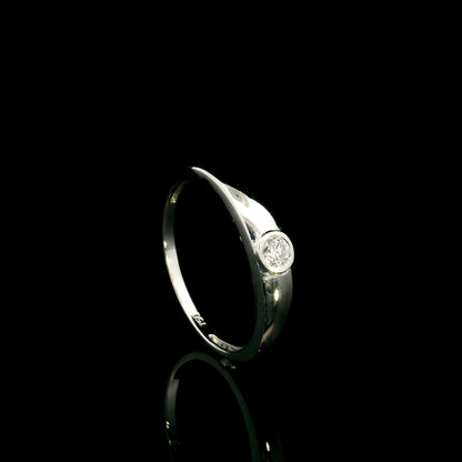 18K white gold bezel set solitaire diamond ring featuring a 0.11 carat natural round brilliant diamond with a smooth polished band.