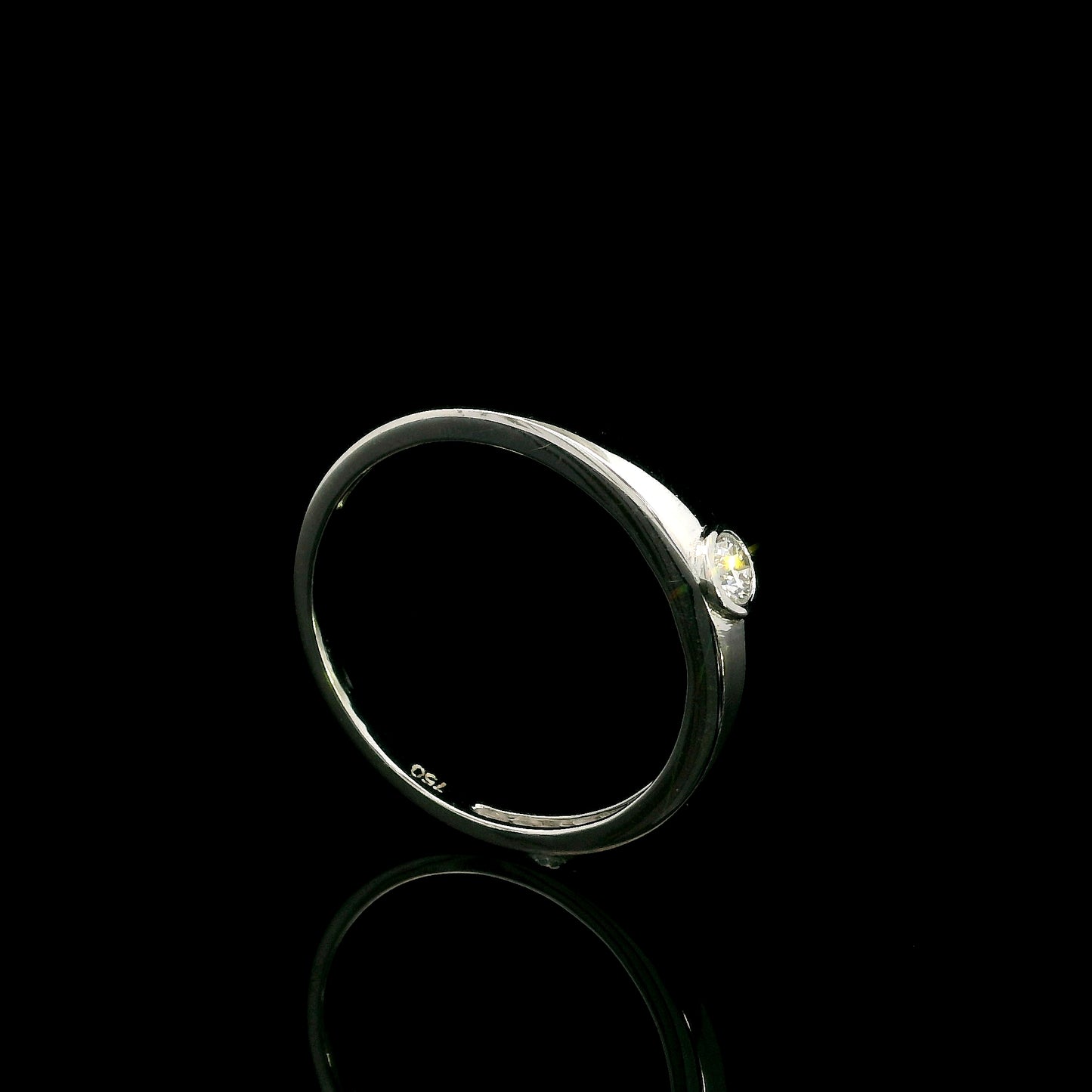 18K white gold bezel set solitaire diamond ring featuring a 0.11 carat natural round brilliant diamond with a smooth polished band.
