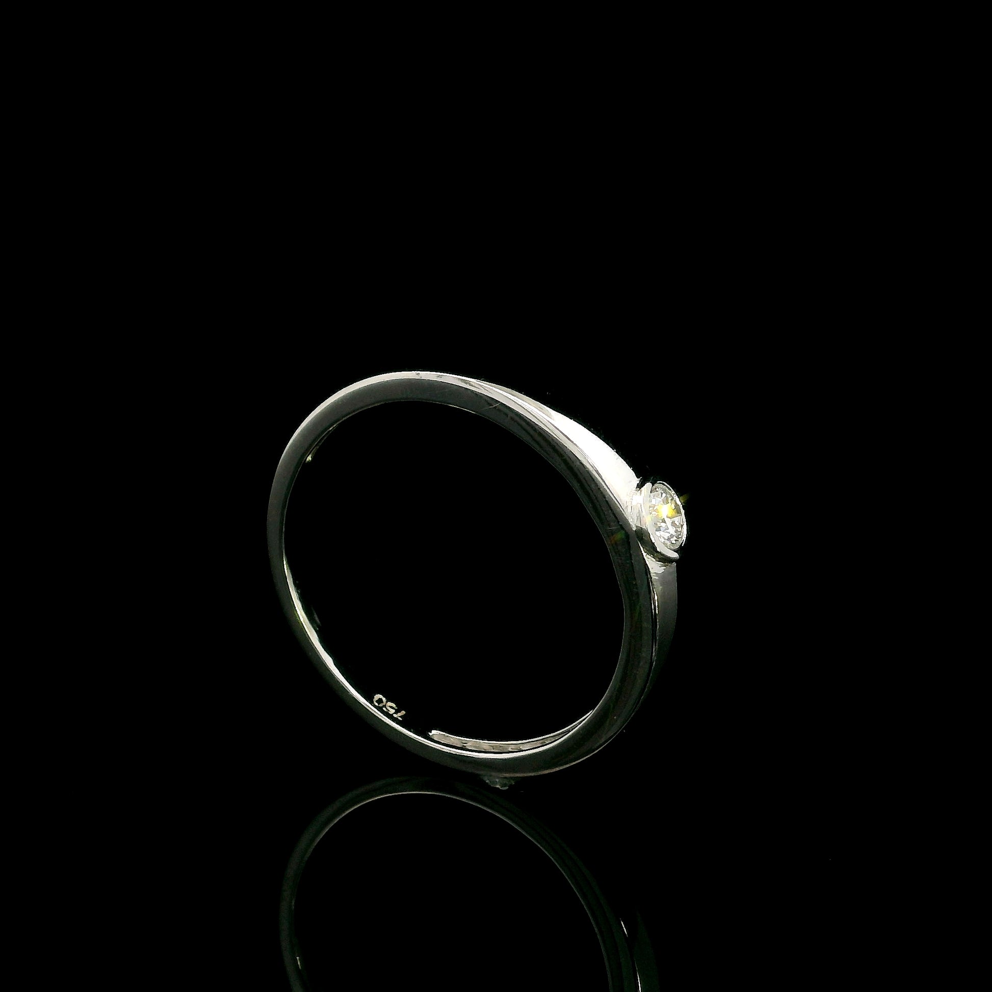 18K white gold bezel set solitaire diamond ring featuring a 0.11 carat natural round brilliant diamond with a smooth polished band.