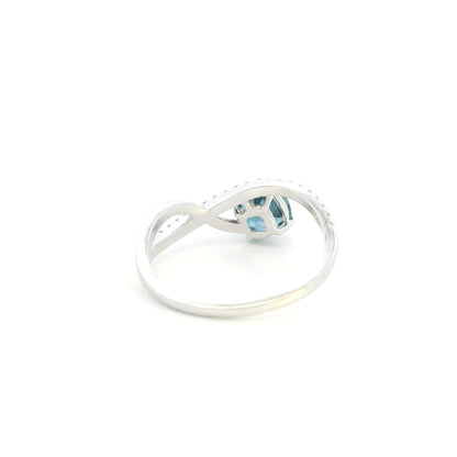 18K white gold twist ring featuring a 1.10 carat natural cushion-cut London Blue Topaz with a diamond-set crossover band and 0.15 carat natural diamonds.