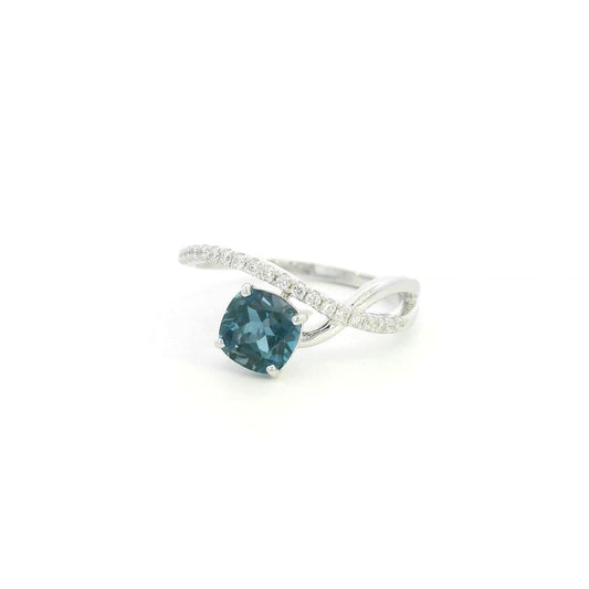 18K white gold twist ring featuring a 1.10 carat natural cushion-cut London Blue Topaz with a diamond-set crossover band and 0.15 carat natural diamonds.