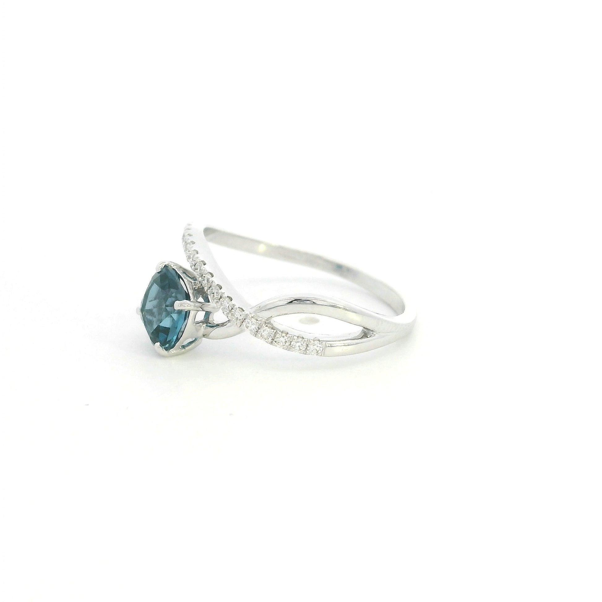 18K white gold twist ring featuring a 1.10 carat natural cushion-cut London Blue Topaz with a diamond-set crossover band and 0.15 carat natural diamonds.