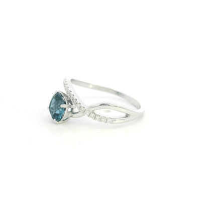 18K white gold twist ring featuring a 1.10 carat natural cushion-cut London Blue Topaz with a diamond-set crossover band and 0.15 carat natural diamonds.