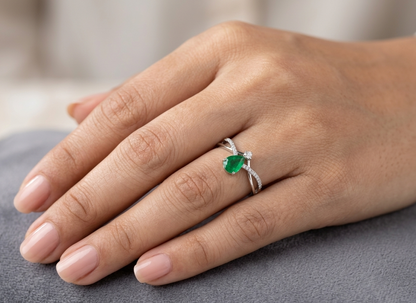 Pear shaped natural emerald and diamond ring in 18K white gold with diamond accented sculpted shoulders
