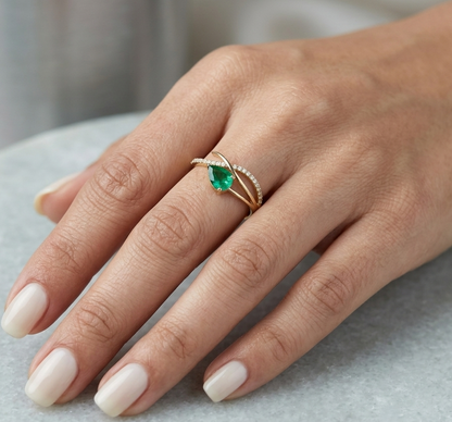 18K yellow gold emerald crossover ring featuring a 0.51 carat natural emerald and 0.09 carat natural diamond accent band.